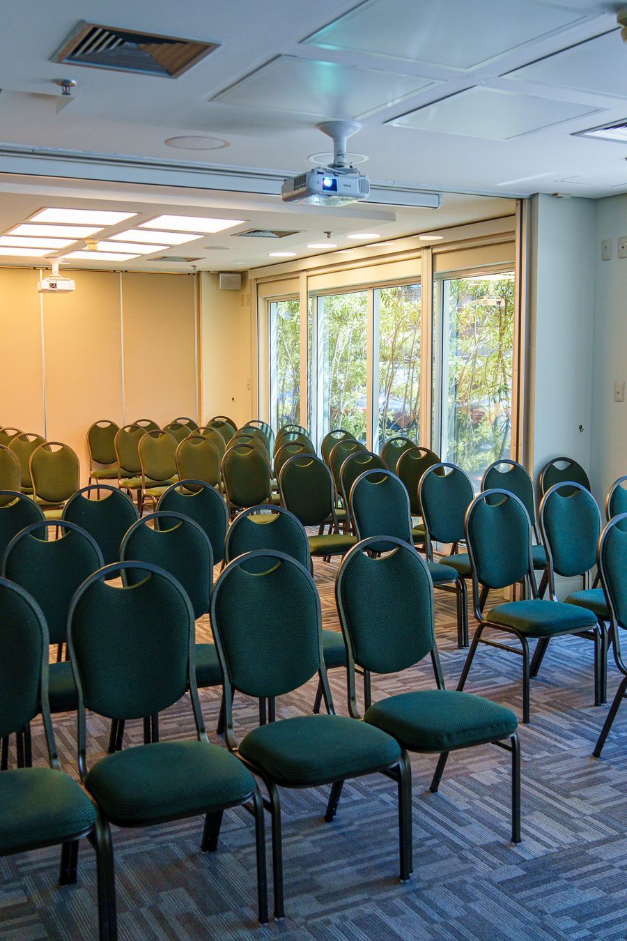 Uma sala de conferências cheia de cadeiras verdes e um projetor.