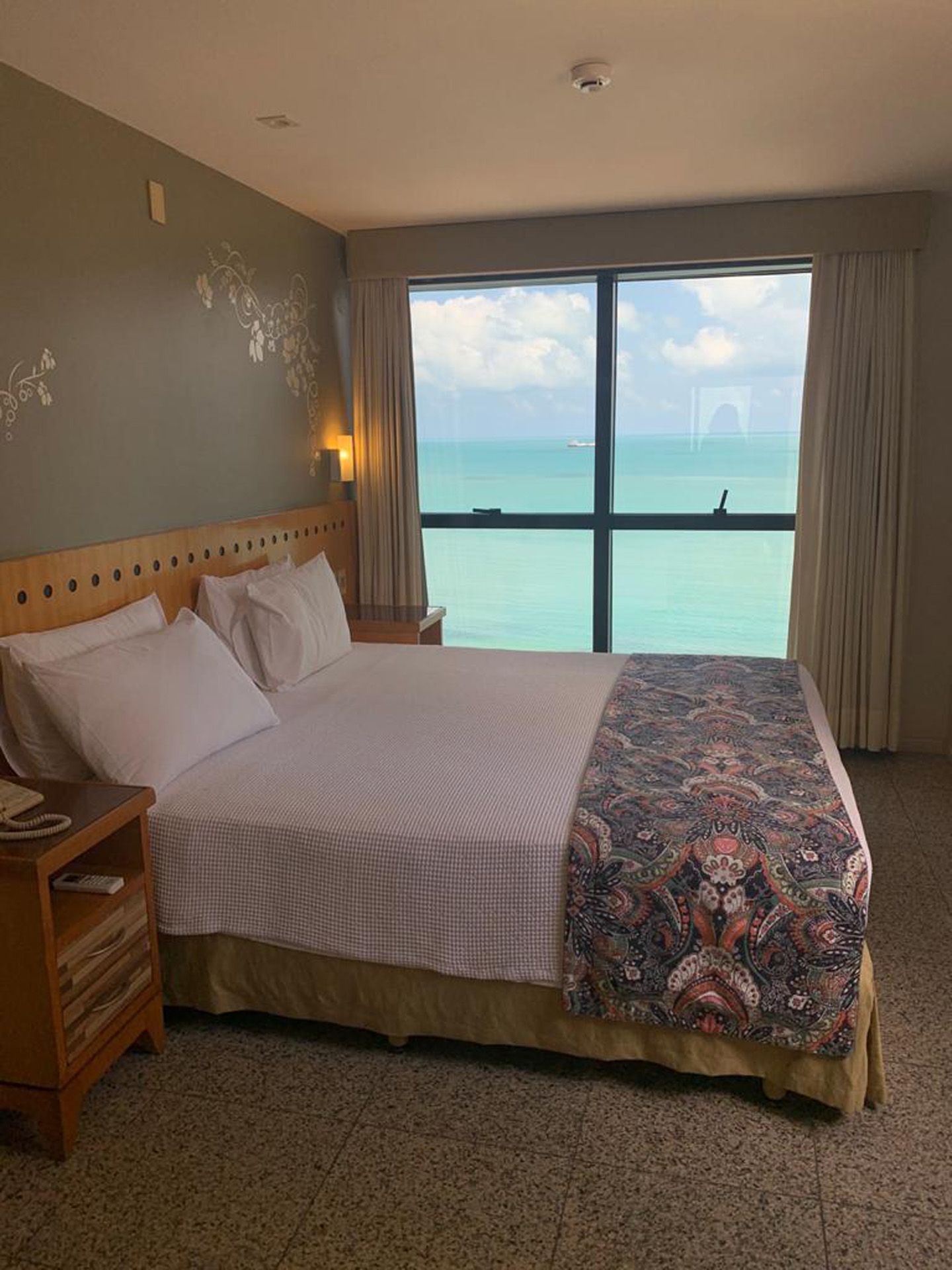 Um quarto de hotel com uma cama king size e uma grande janela com vista para o oceano.