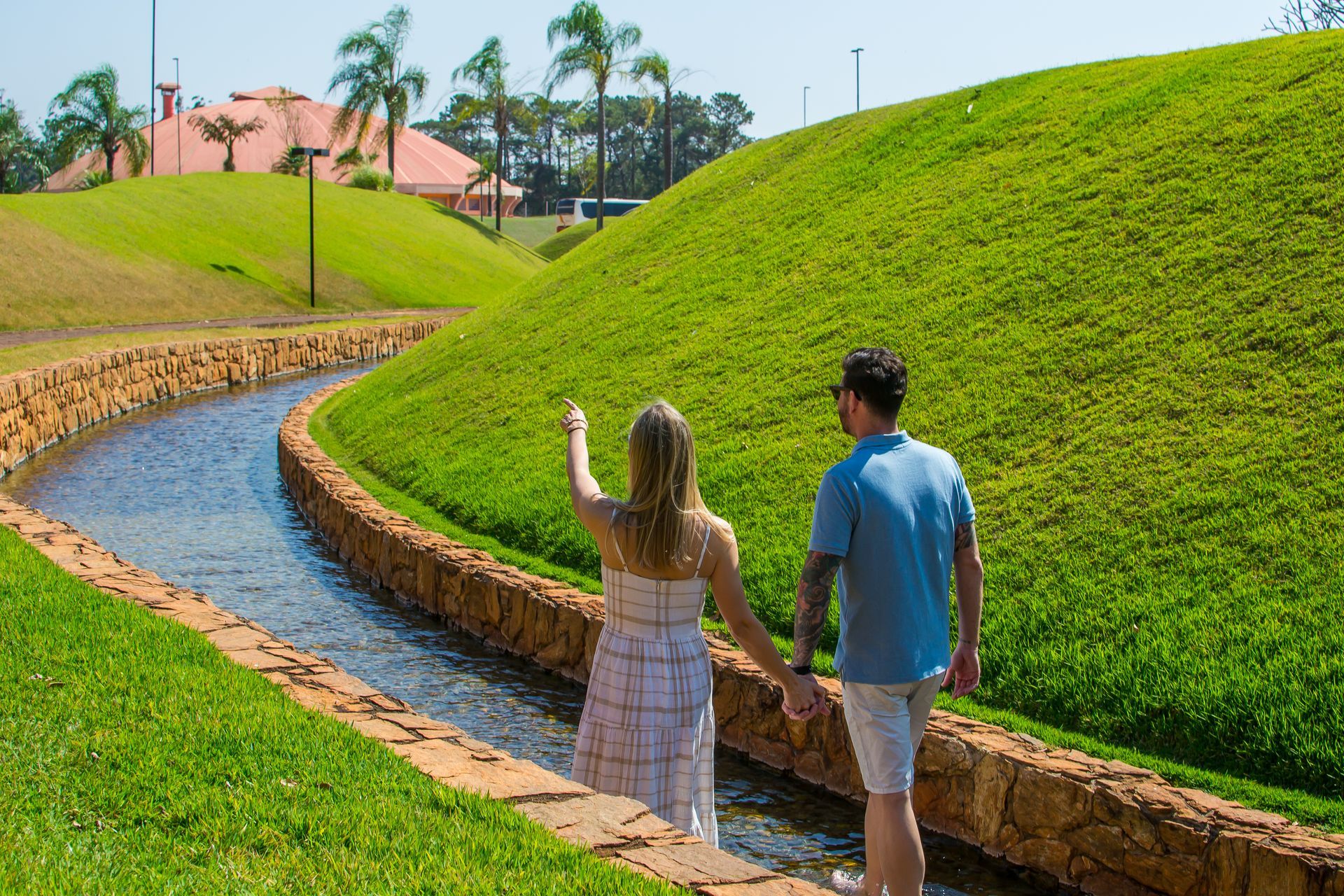 Um homem e uma mulher estão caminhando rio abaixo de mãos dadas.