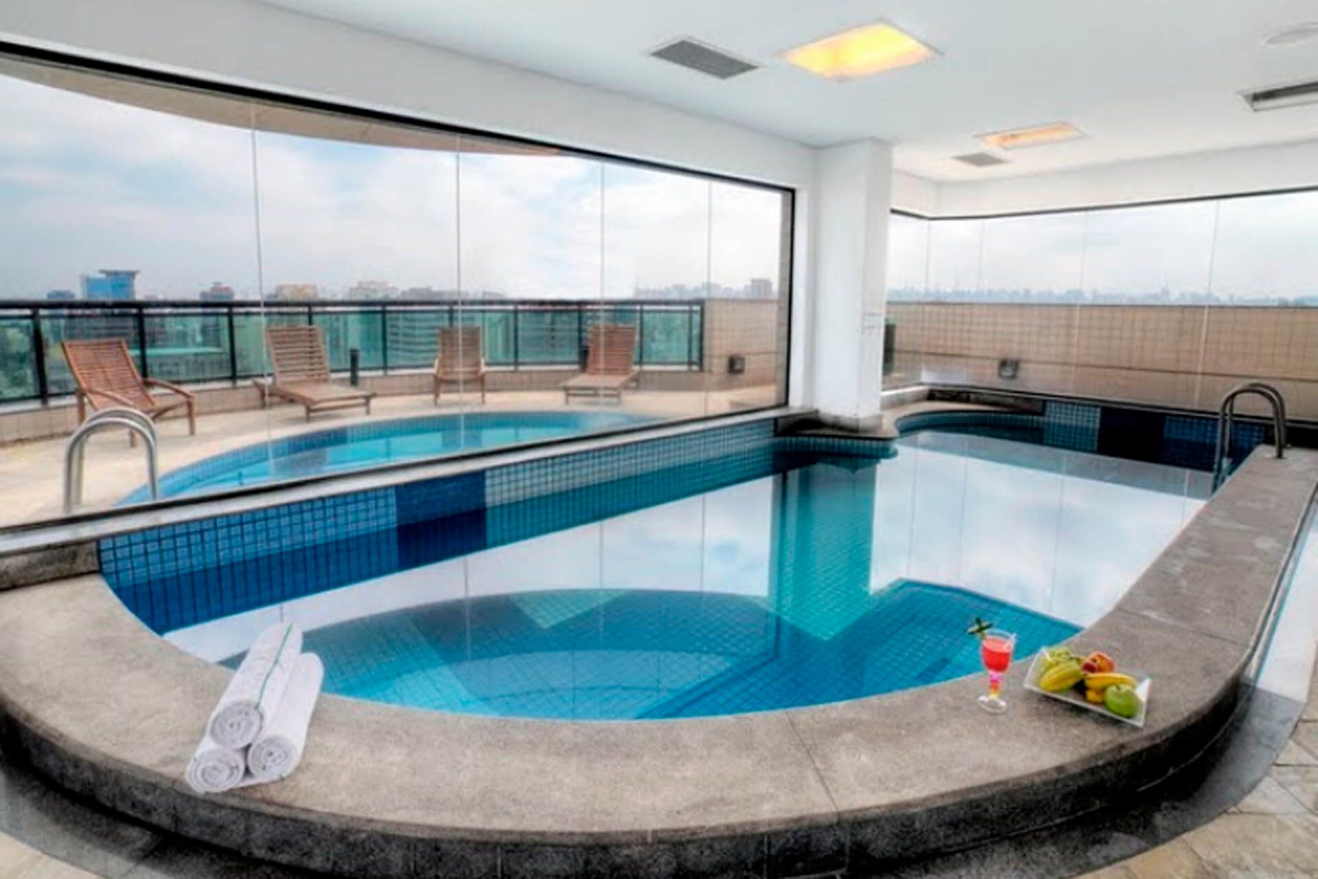almofadas com piscina e palmeiras ao fundo