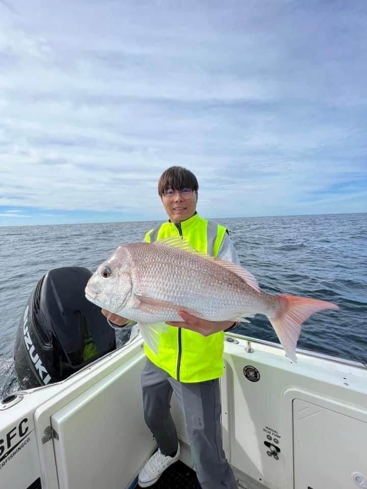 A man is holding a large fish on a boat in the ocean.