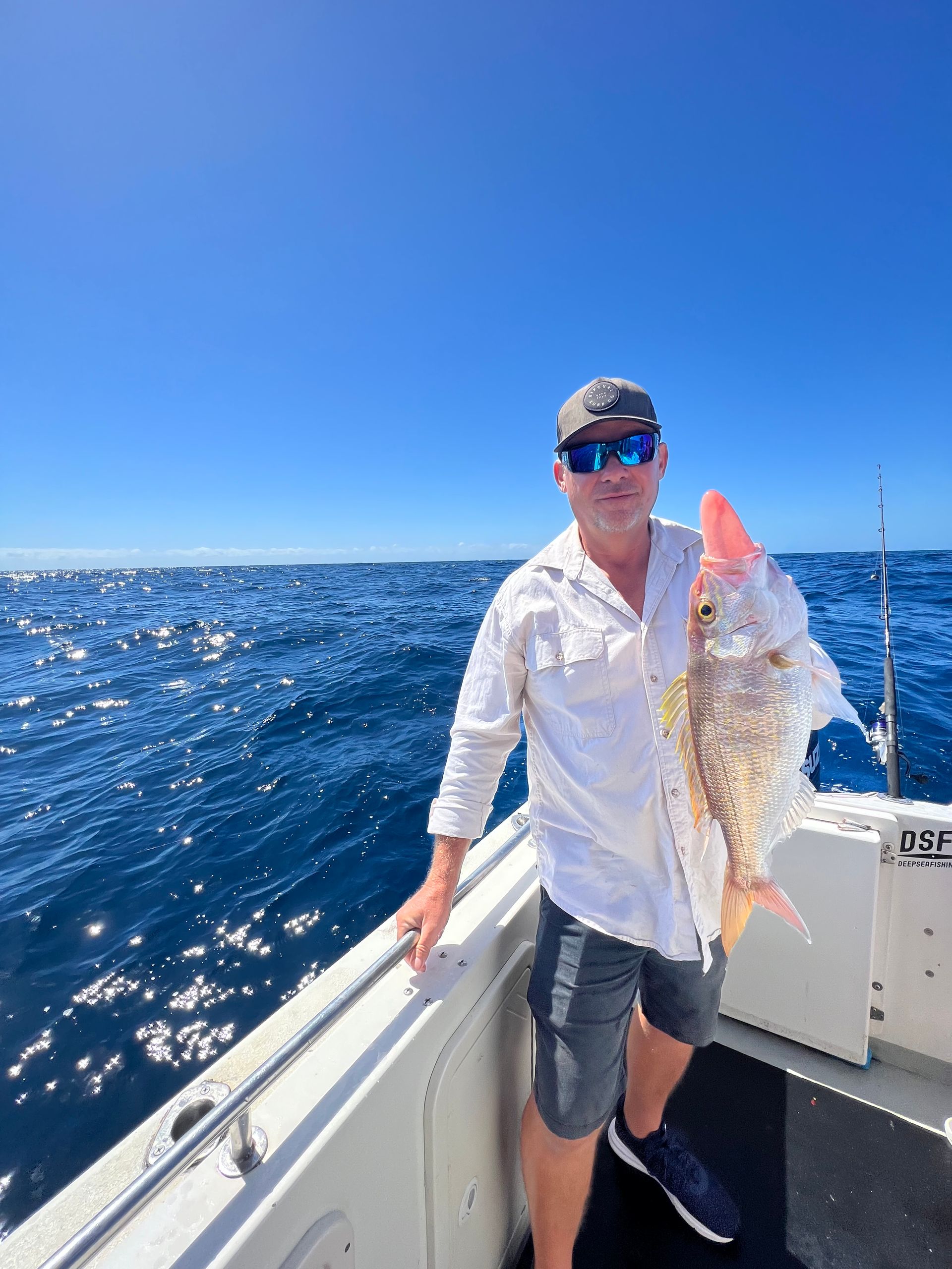 A man is standing on a boat holding a fish.