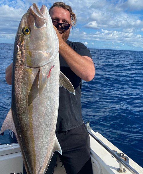 Man Holding a Amberjack Fish on the Yacht | Fishing Charters Sunshine Coast 