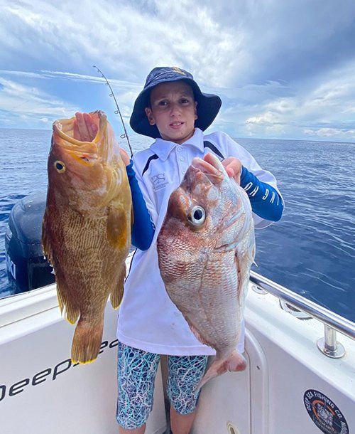 Kid Holding Two Fresh Fish He Caught on Fishing Charters on the Sunshine Coast