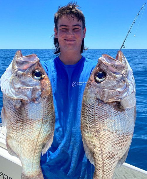 Man Holding Two Heavy Pearlie Fish That He Caught  from  Fishing Charters in Sunshine Coast