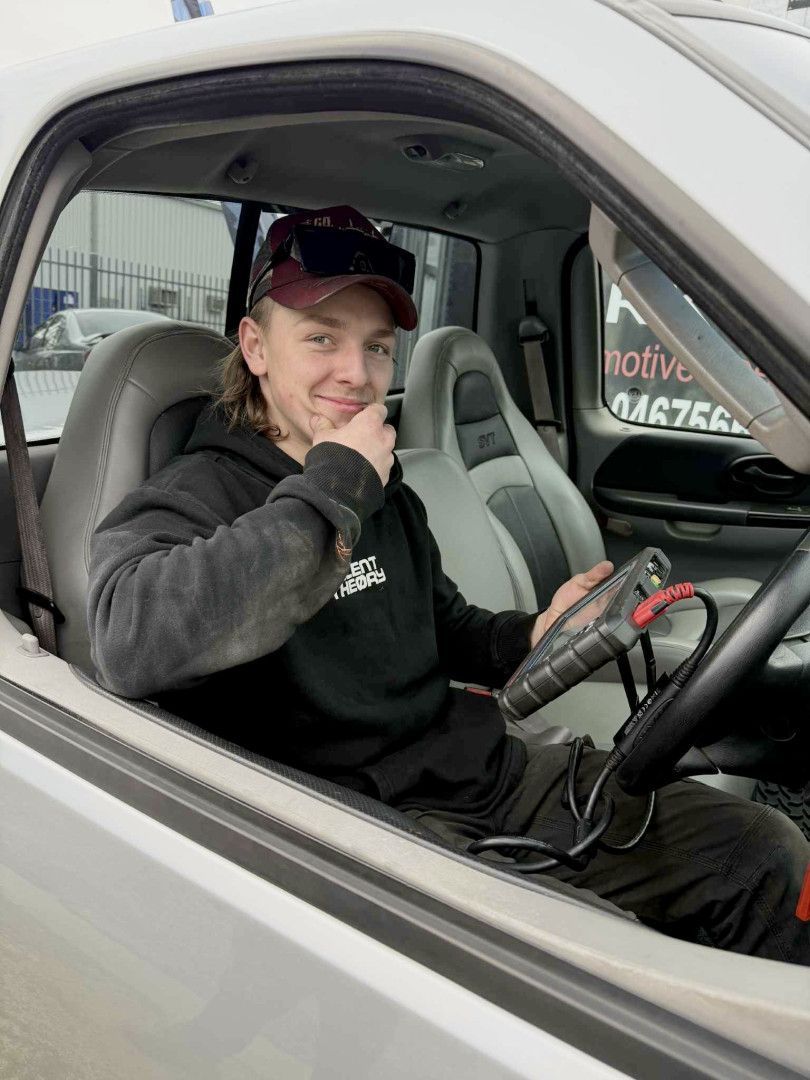 Man in black hoodie smiles from driver's seat of a silver truck, holding a diagnostic tool - Gricey's Workshop Automotive Specialist in West Wodonga, VIC