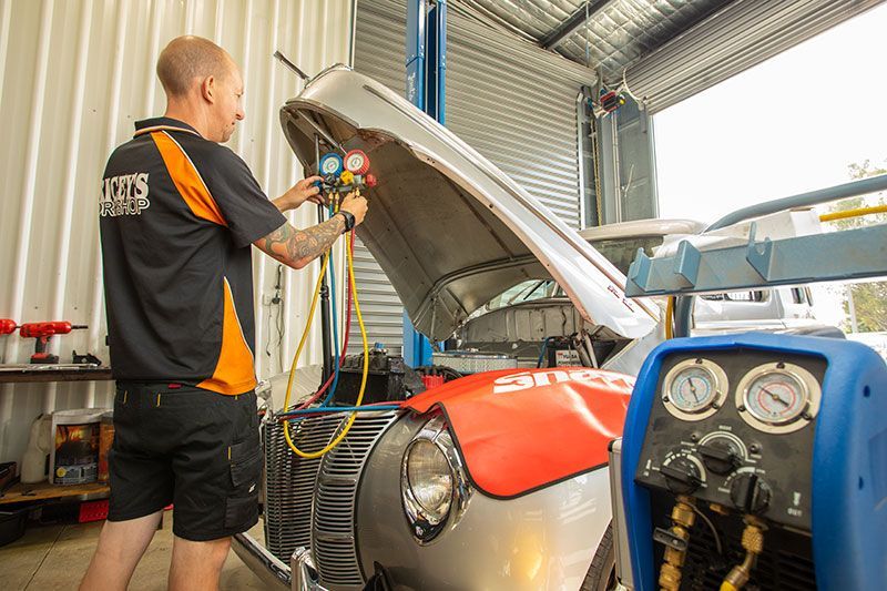 A Man is Working on a Car With the Hood Open in a Garage — Gricey's Workshop Automotive Specialist in West Wodonga, VIC