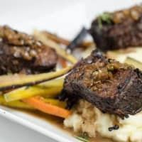 A close up of a plate of food with meat and vegetables on a table.