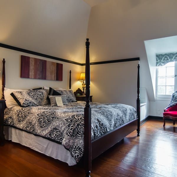 A bedroom with a four poster bed and a red chair
