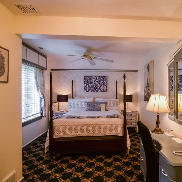 A bedroom with a four poster bed and a ceiling fan