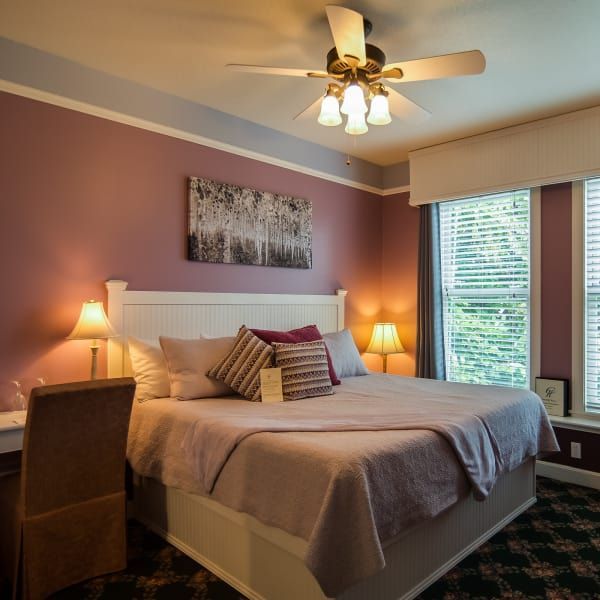 A bedroom with a large bed and a ceiling fan