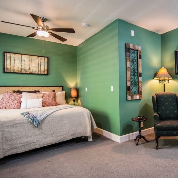 A bedroom with green walls and a ceiling fan