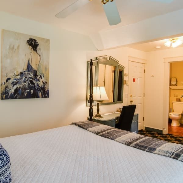 A bedroom with a painting on the wall above the bed