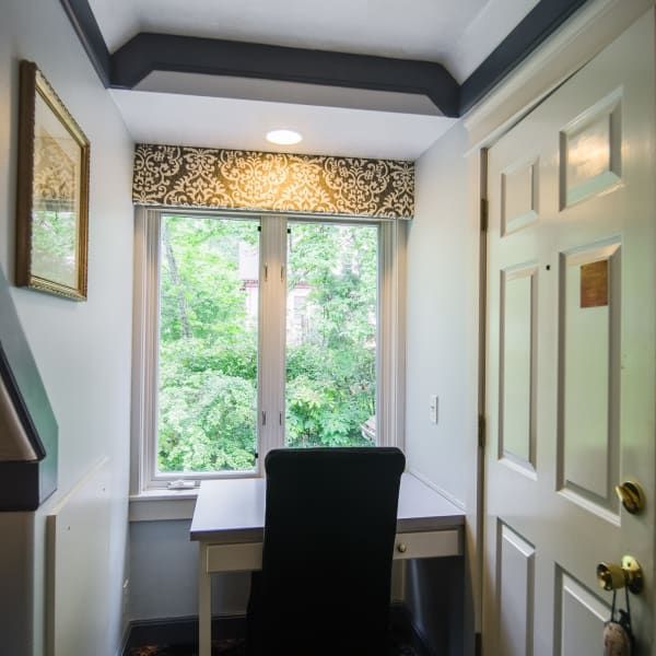 A small room with a desk and chair in front of a window