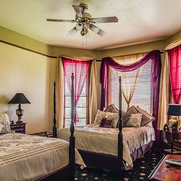 A bedroom with two beds and a ceiling fan