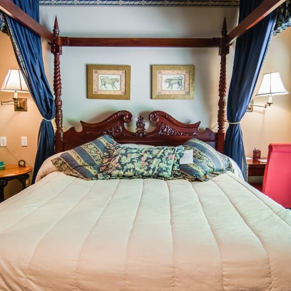 A four poster bed with two pictures on the wall above it