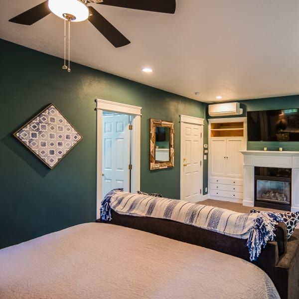 A bedroom with a ceiling fan and a fireplace