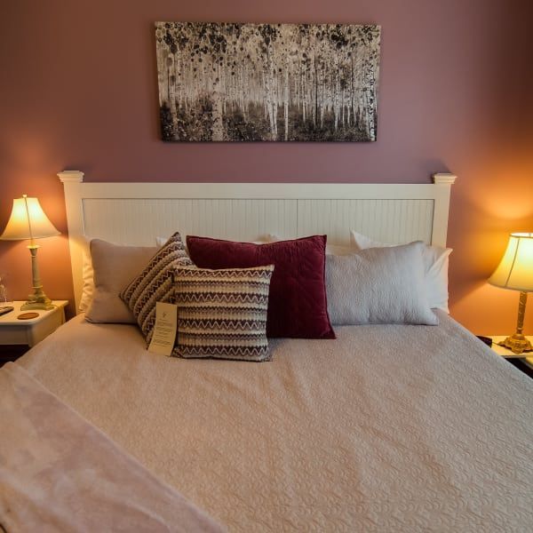 A bed with pillows and a painting on the wall above it