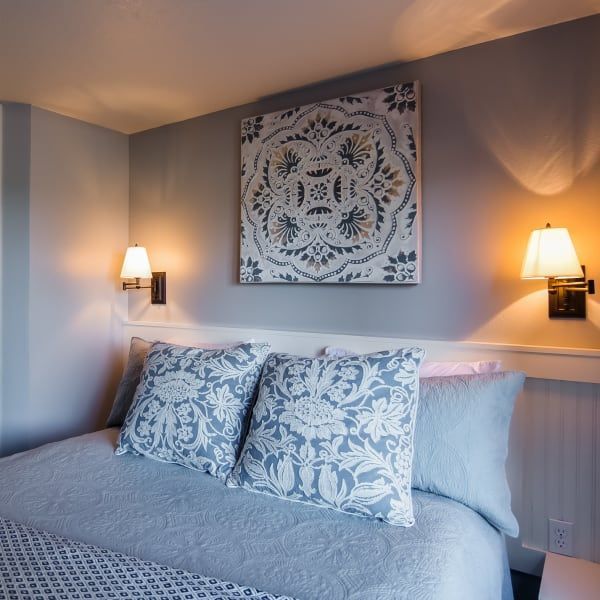 A bedroom with a painting on the wall above the bed