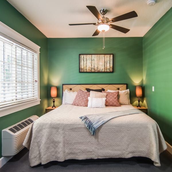 A bedroom with green walls and a ceiling fan