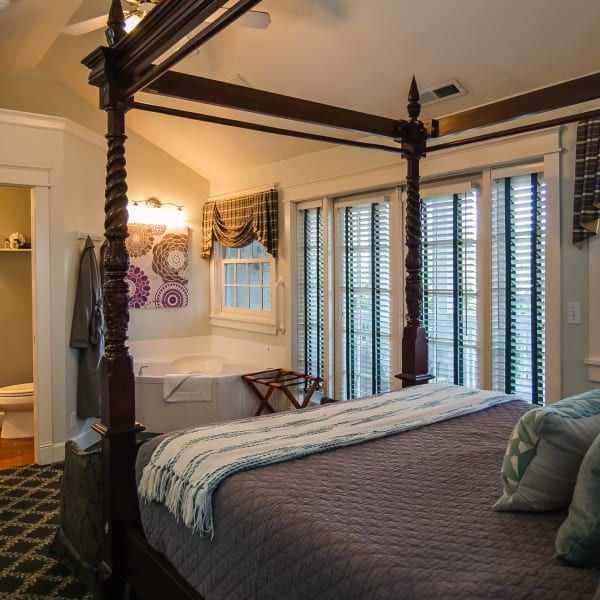 A bedroom with a four poster bed and a bathtub