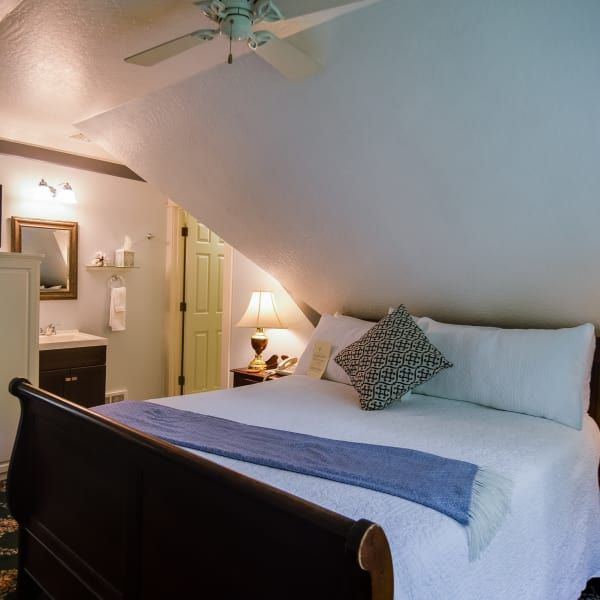 A bedroom with a sleigh bed and a ceiling fan