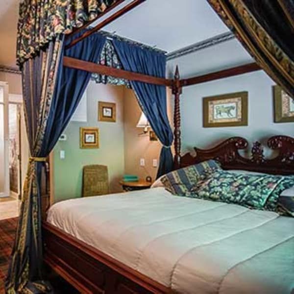 A bedroom with a four poster bed and blue curtains