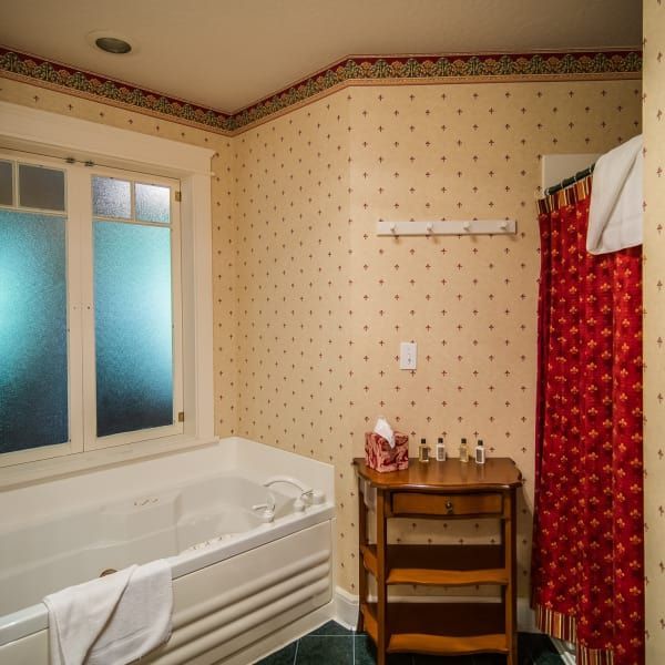 A bathroom with a jacuzzi tub and a red shower curtain