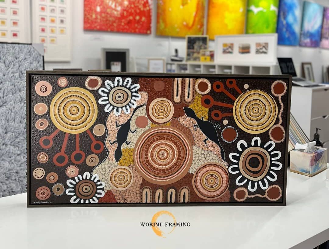 A Painting Is Sitting On A Table In Front Of A Wall Of Paintings — Worimi Framing Service In Adamstown, NSW