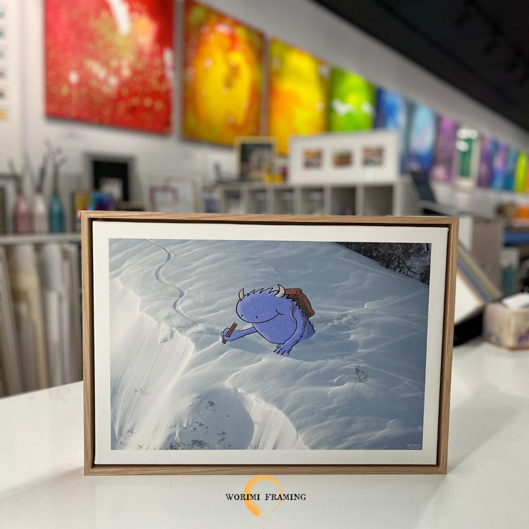 A Framed Picture Of A Cartoon Character Laying In The Snow — Worimi Framing Service In Adamstown, NSW