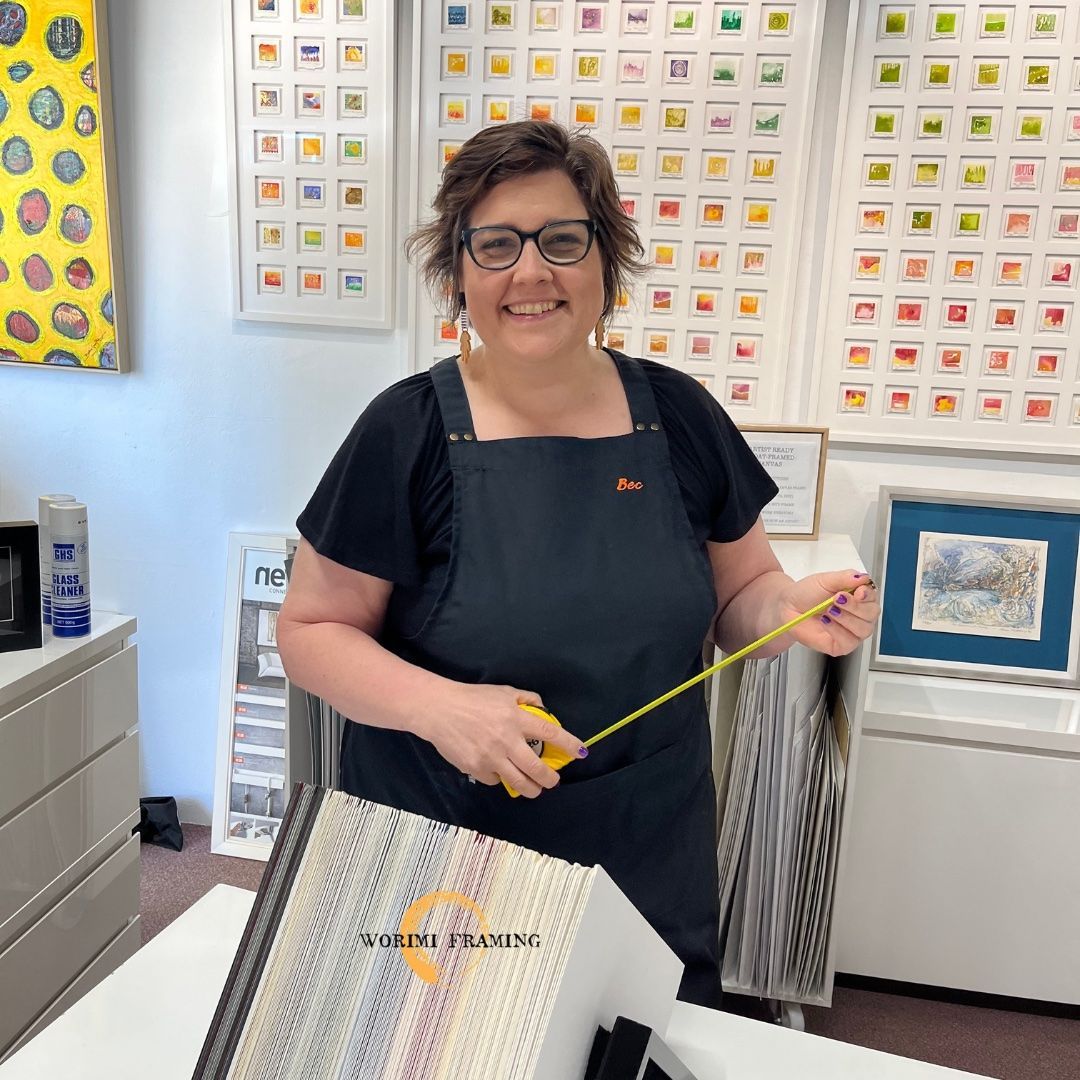 A Women With A Tape Measure And Photo Frames Behind Her— Worimi Framing Service In Lake Macquarie, NSW