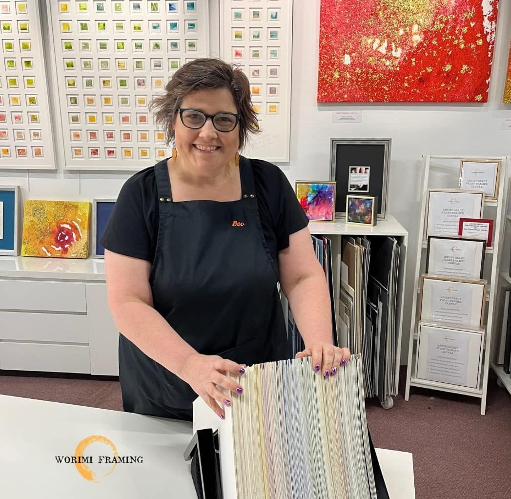 A Woman In A Black Apron Is Holding A Piece Of Paper — Worimi Framing Service In Adamstown, NSW