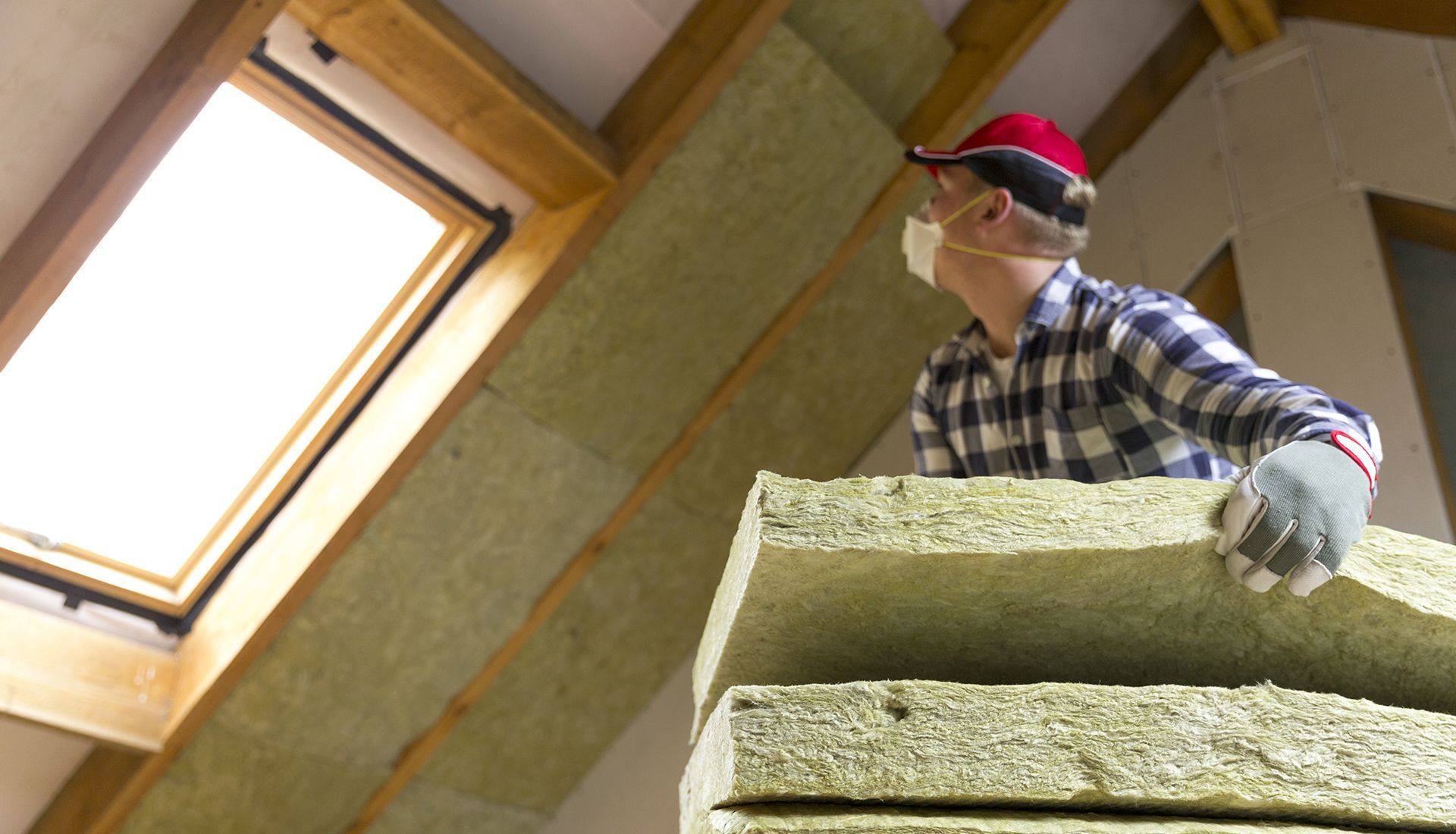 A man wearing a mask and gloves is holding a stack of rockwool blocks.
