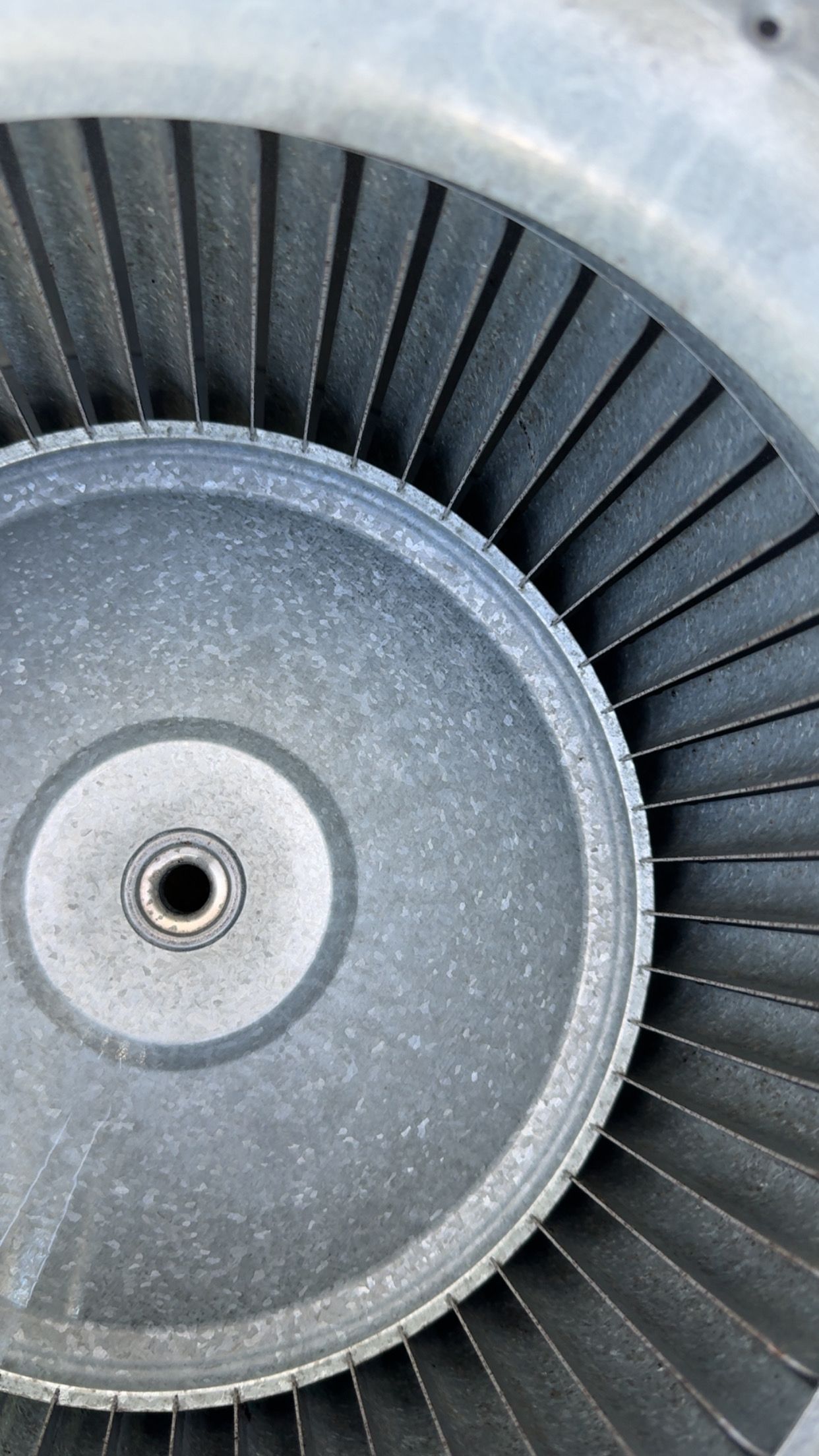 Close-up of a gray blower wheel with curved blades.