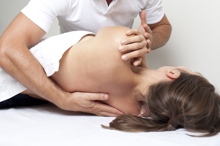 A Woman is Laying on a Table Getting a Massage From a Man — Mark O'Brien Chiropractic in West End, QLD