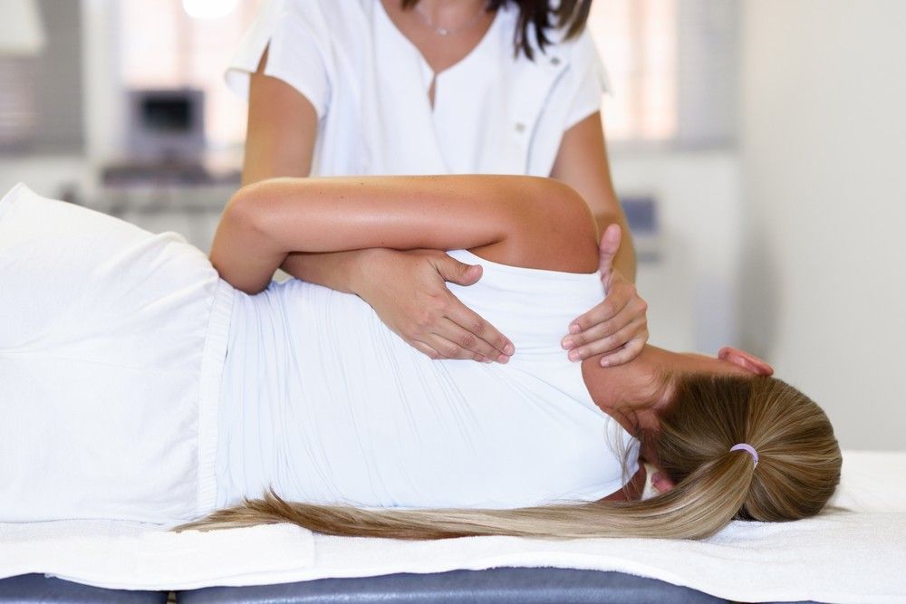 A Woman is Laying on a Table Getting a Massage — Mark O'Brien Chiropractic in West End, QLD