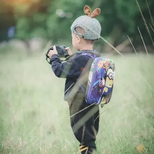 A Little Boy is Standing in a Field Holding a Camera — Mark O'Brien Chiropractic in West End, QLD