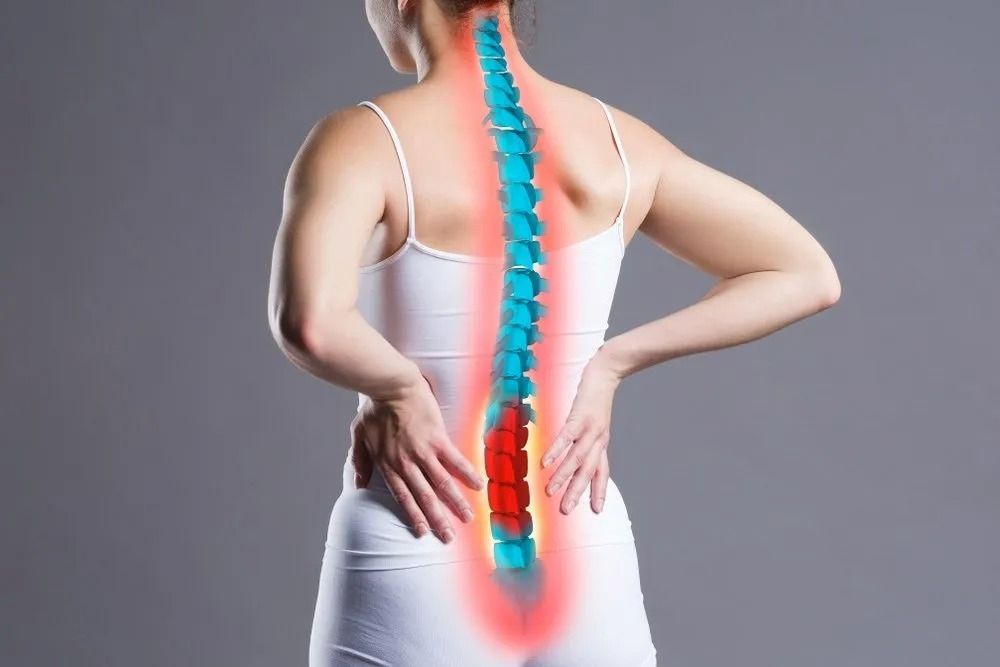 A Woman is Holding Her Back in Pain Because of a Backache — Mark O'Brien Chiropractic in West End, QLD