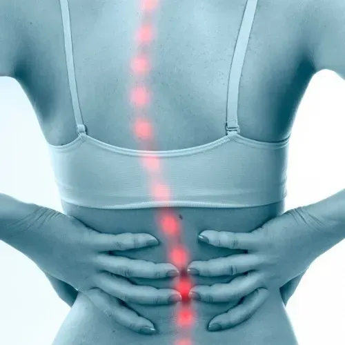 A Woman is Holding Her Back in Pain — Mark O'Brien Chiropractic in West End, QLD