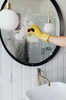 A person is cleaning a bathroom mirror with a sponge.