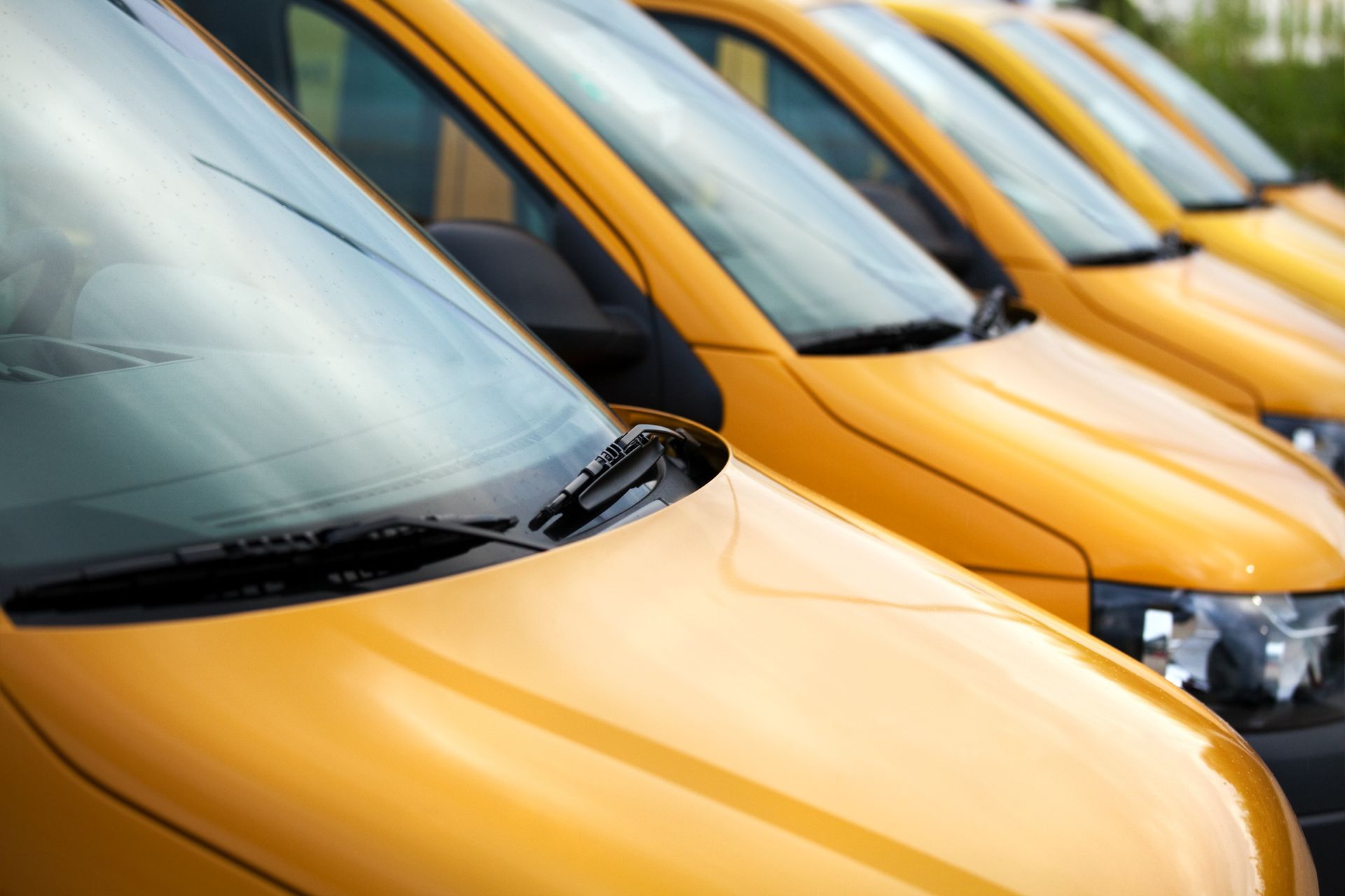 A row of yellow vans are parked next to each other.