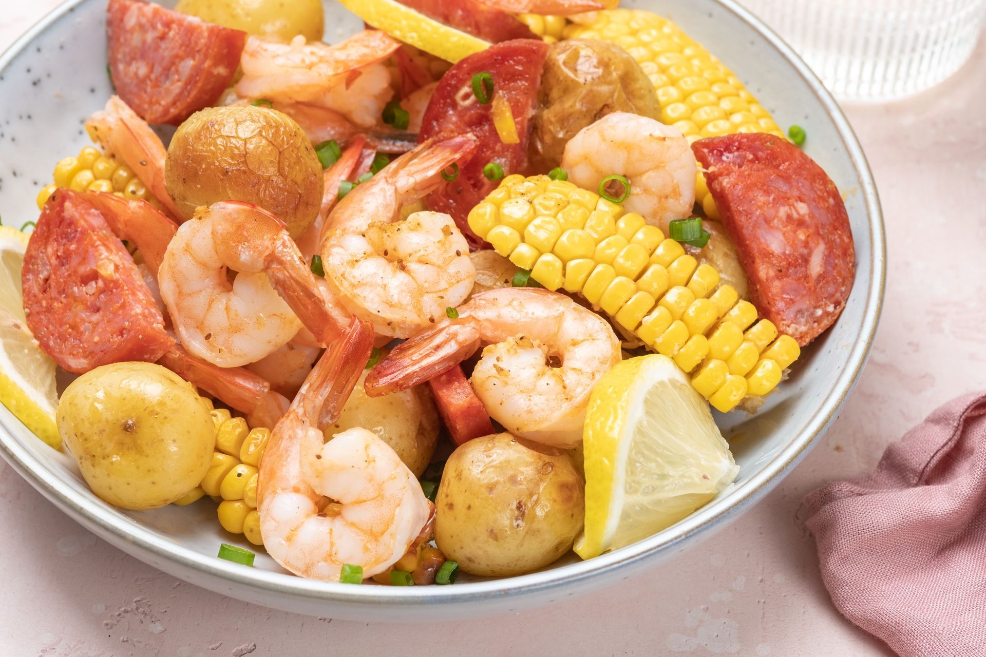 Shrimp boil: shrimp, corn, sausage, potatoes, lemon in bowl, close-up shot.