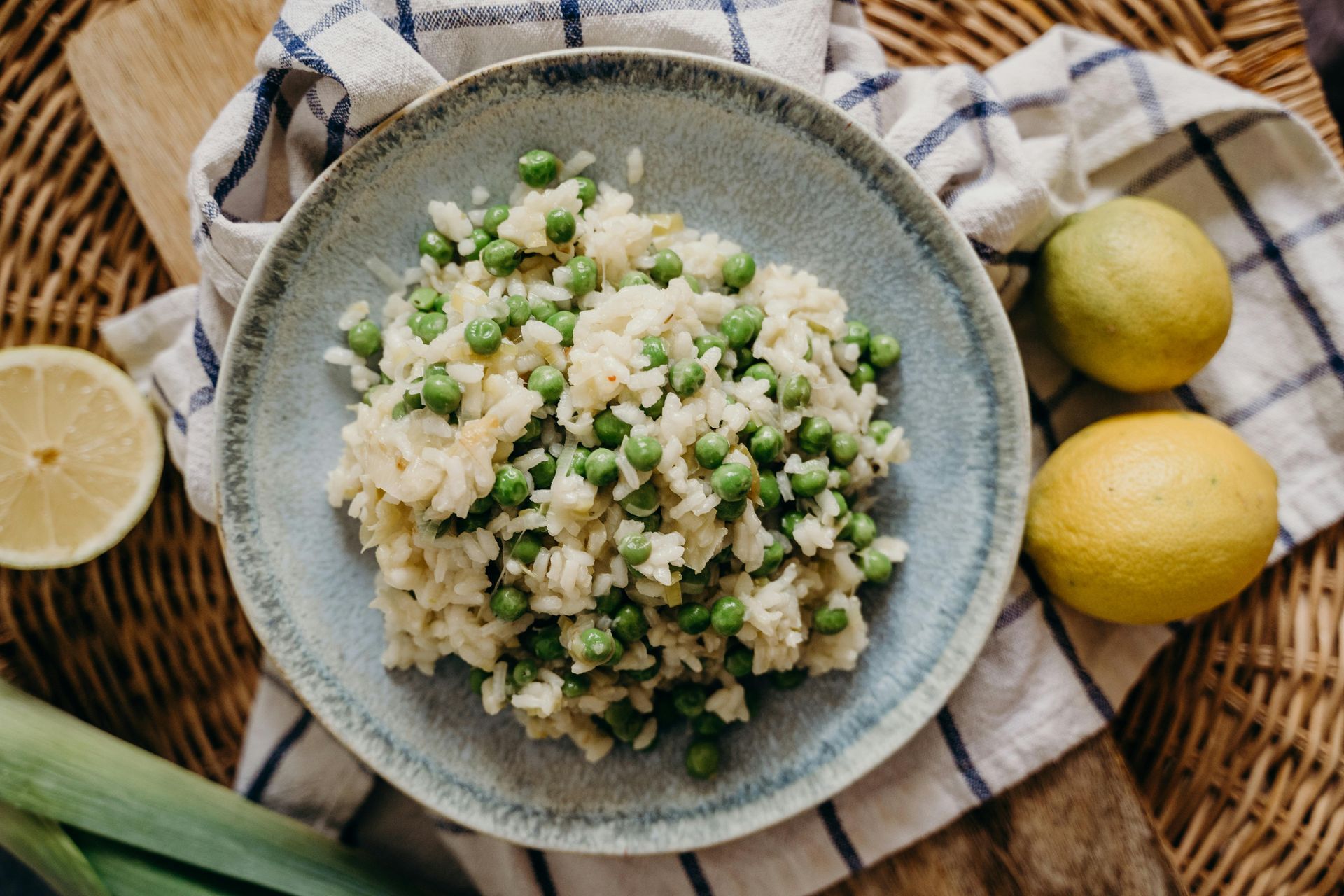 A bowl of rice with peas and lemons on a table. 