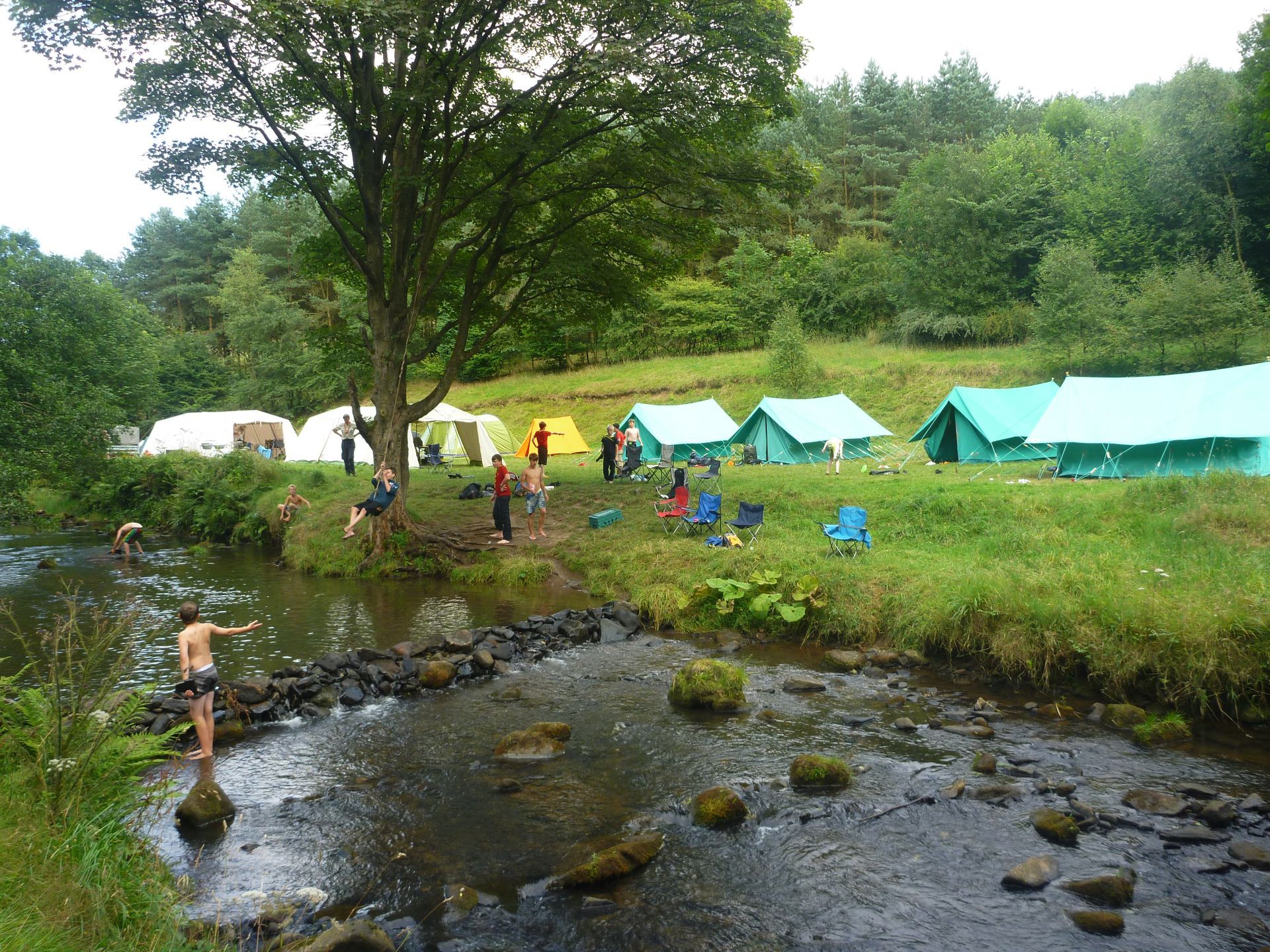 A river runs through a field with tents in the background