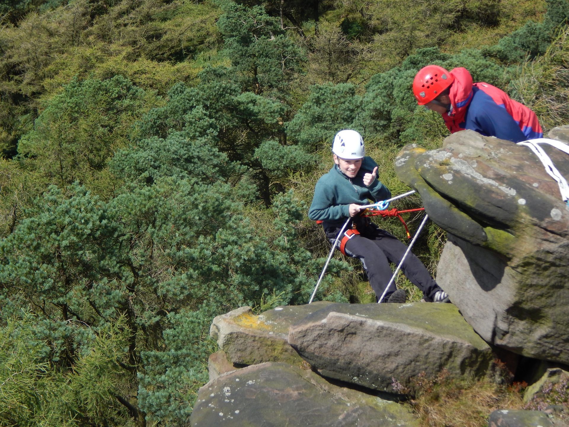 A couple of people are sitting on top of a rock.