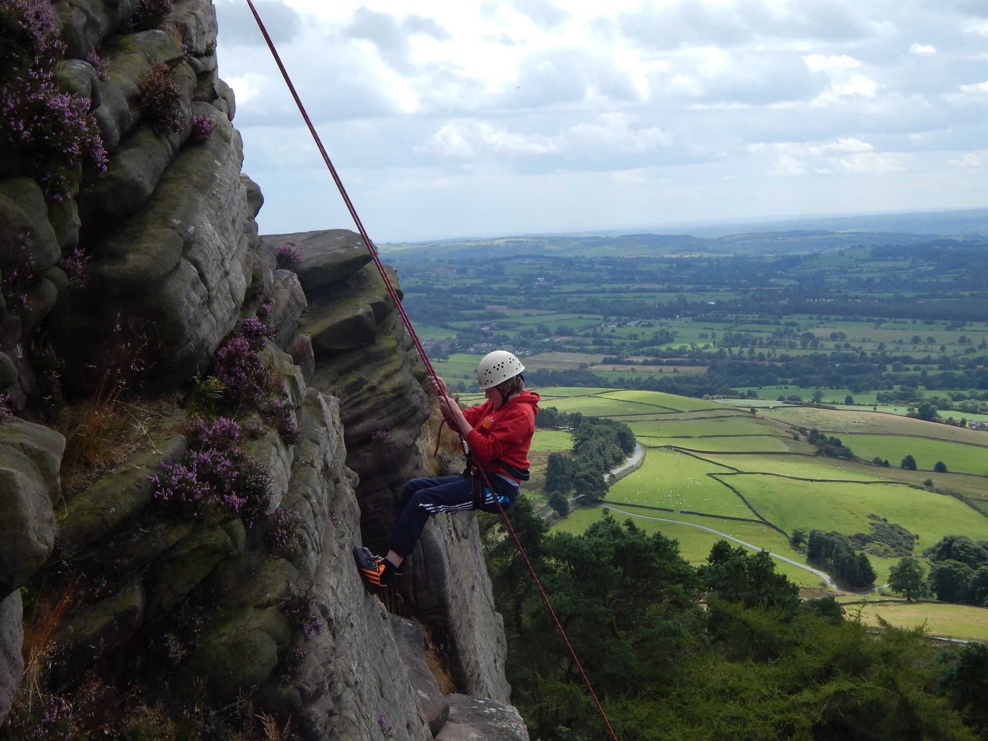 A person is climbing a rock wall with a rope.