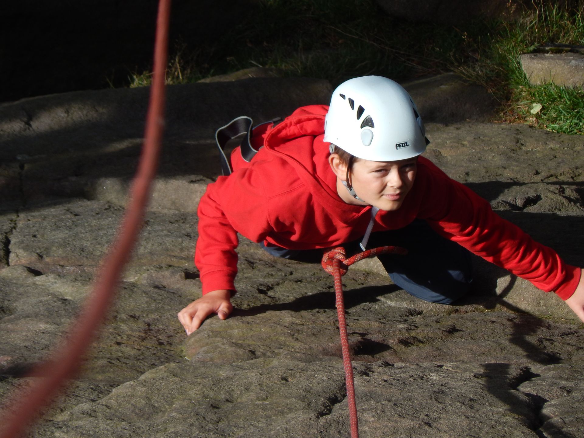 A person wearing a white helmet is crawling on a rock