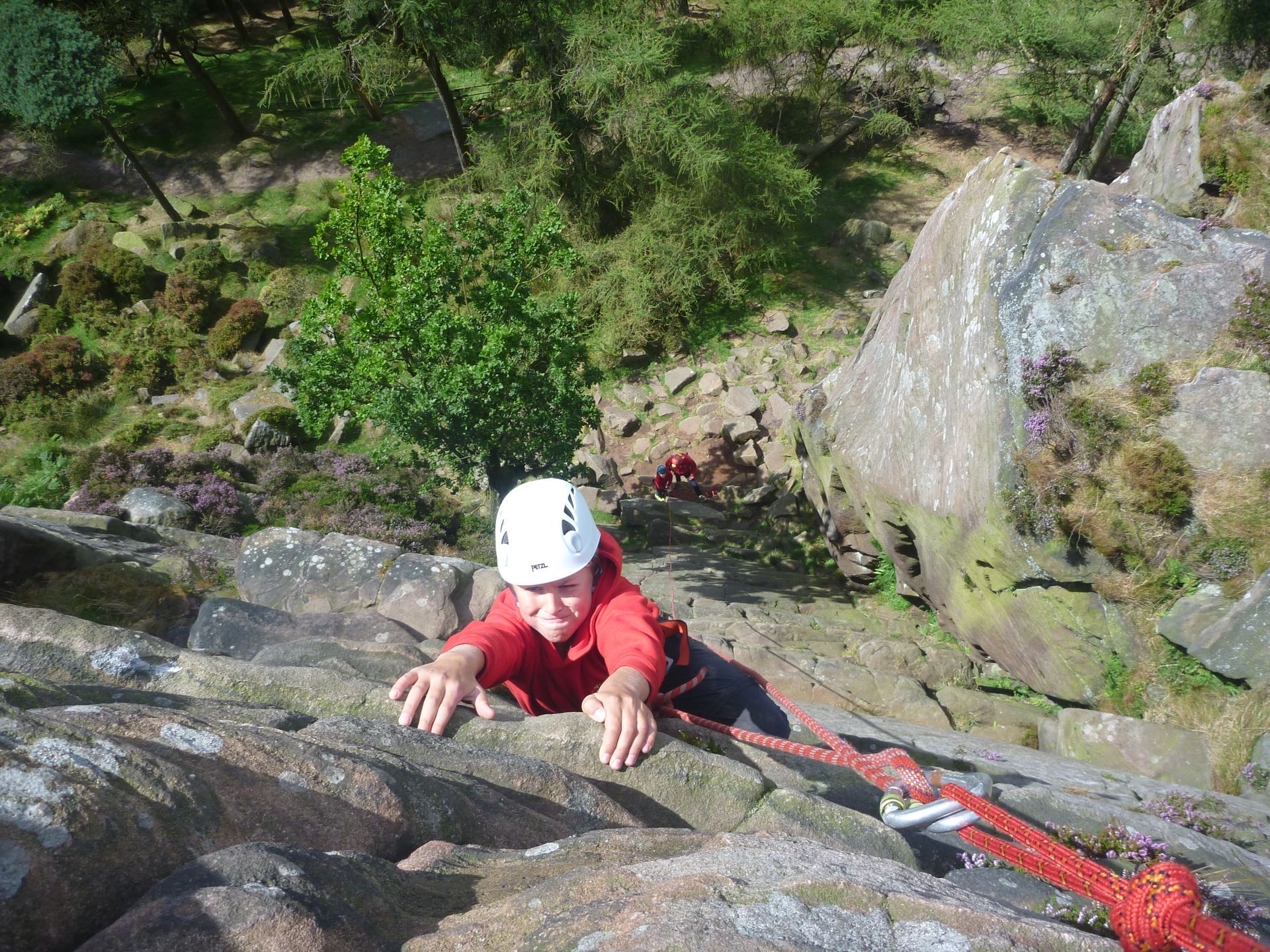 A person is climbing up a rock wall with a rope.