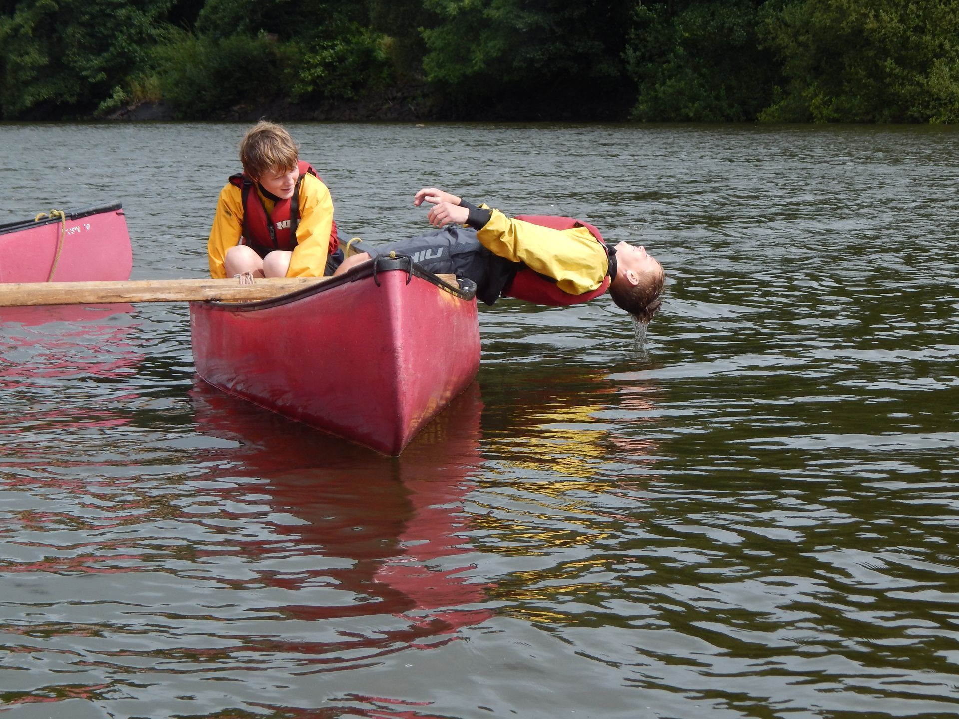 A man is laying on his back in a red canoe