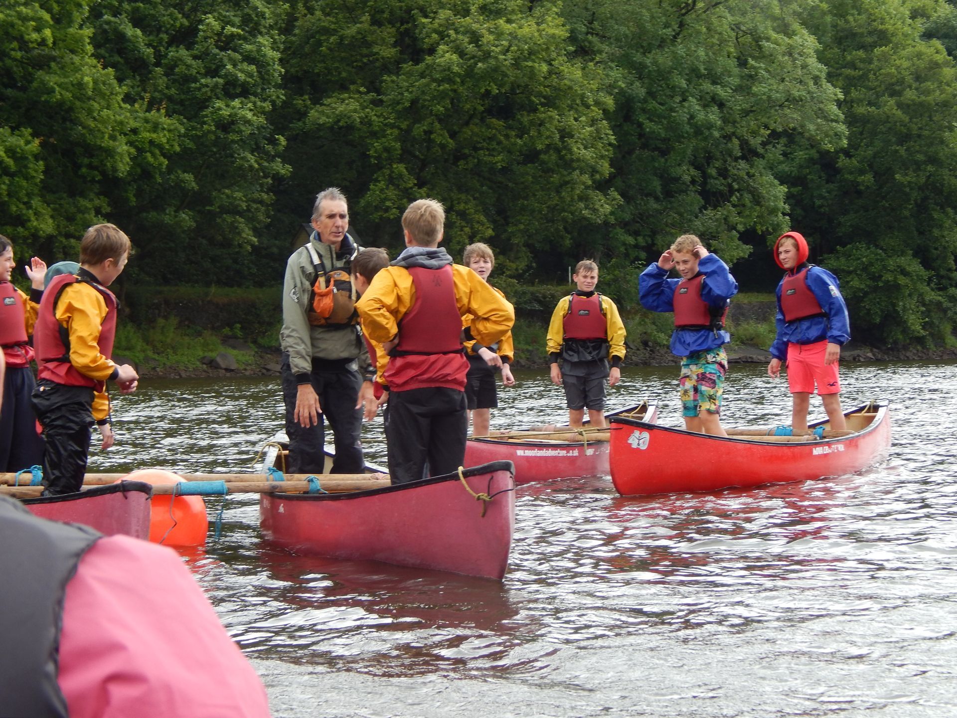 A group of people are in red canoes on a lake